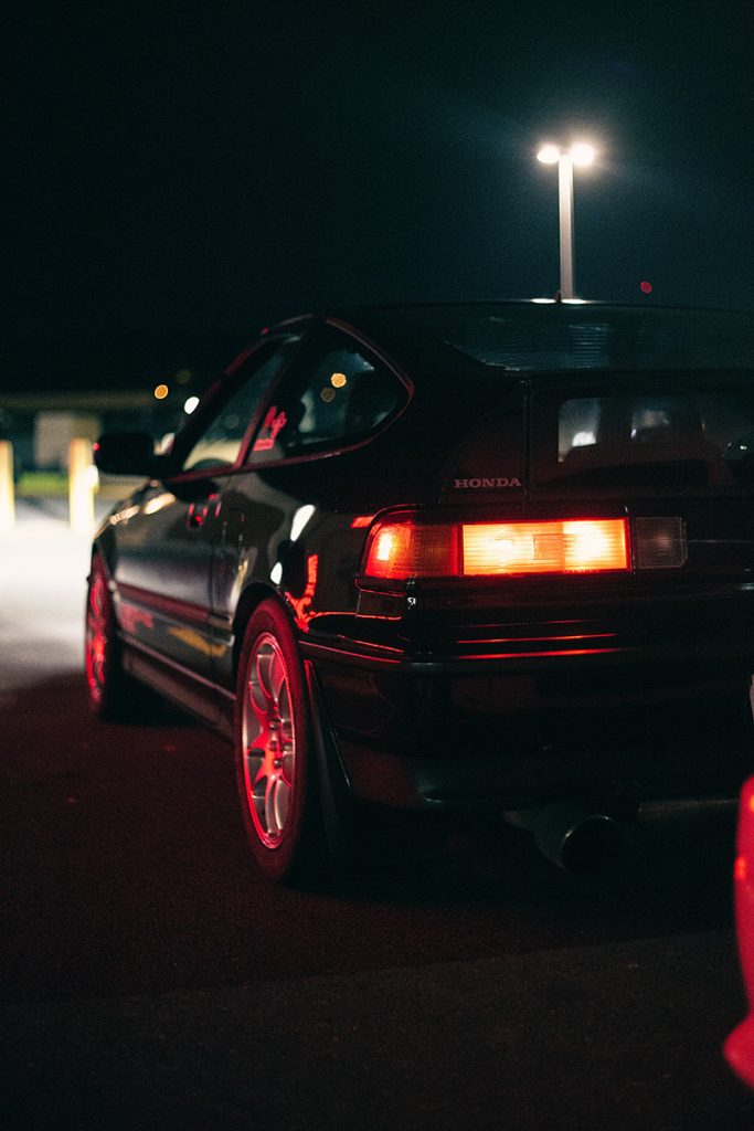 Left tail light of a Honda Civic in a parking lot at night